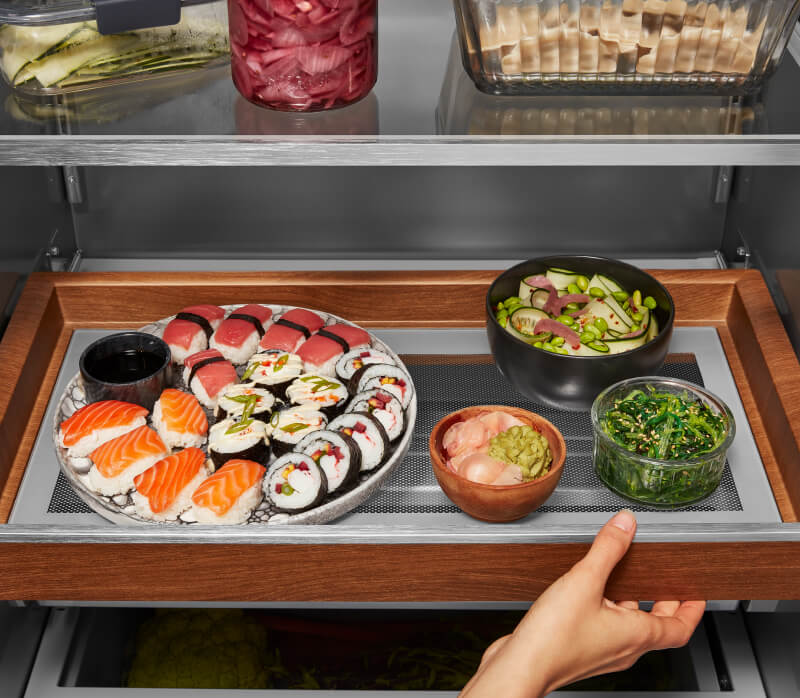 KitchenAid® Built-In Side-by-Side Refrigerator Sliding Storage Tray holding a tray of sushi and other foods