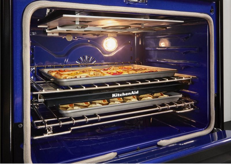 An open oven with trays of food.