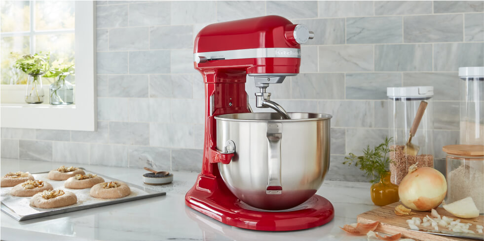 A red KitchenAid® Stand Mixer on a countertop with finished pastries.