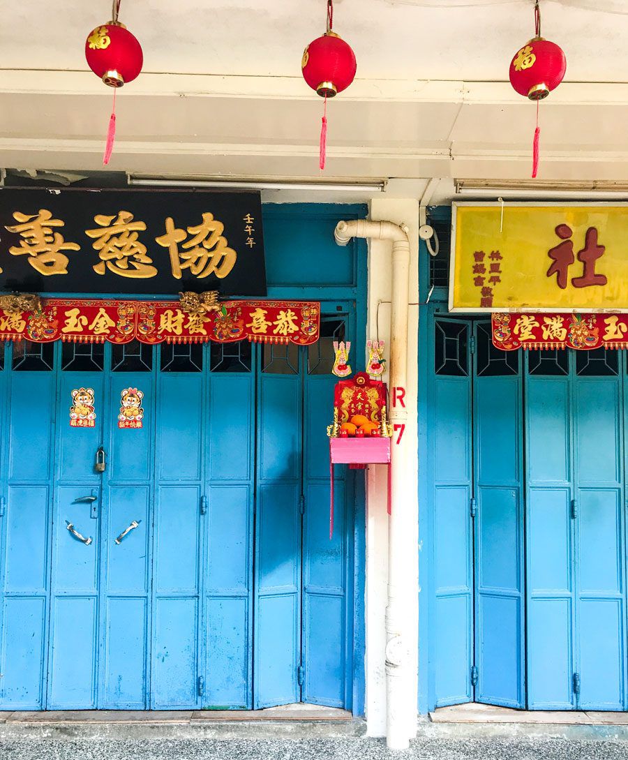 Exterior of a home with Lunar New Year decorations and offerings hanging from the blue doors.
