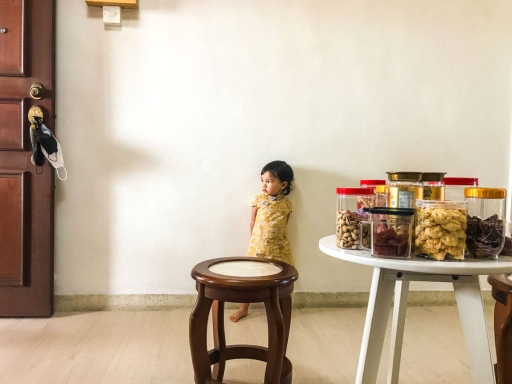A child standing behind a stool and table with assorted treats in different containers.