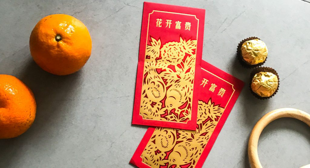 Lunar New Year cards on a table with oranges, candies and wooden hoop.