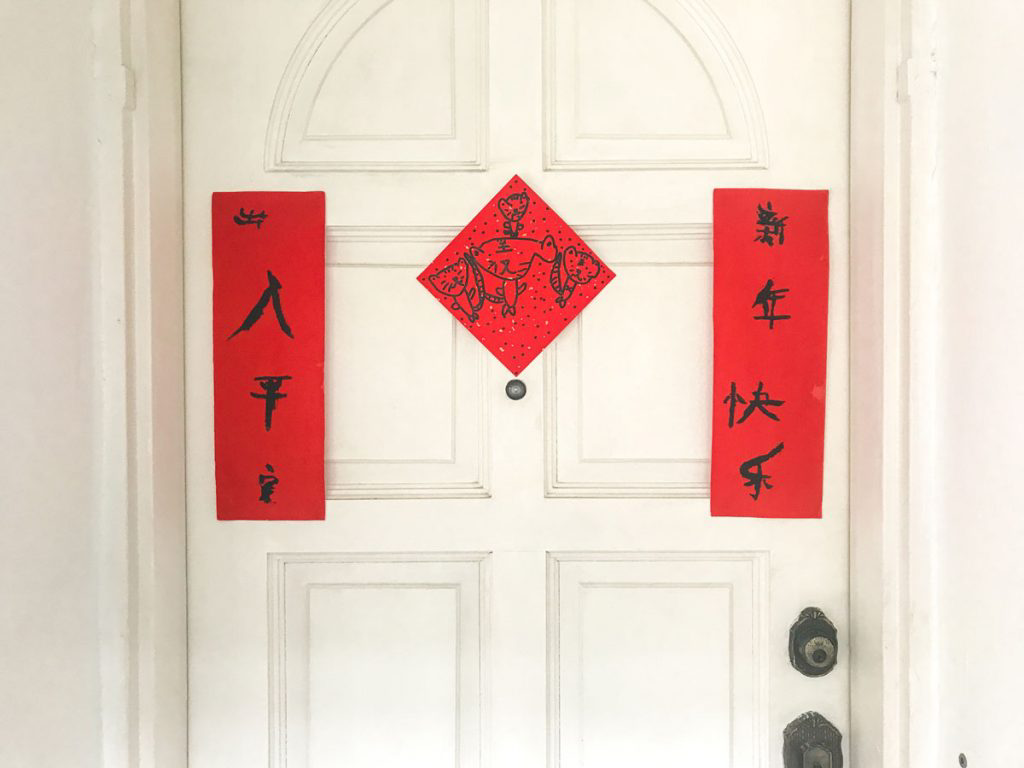 A white door with Lunar New Year decorations hanging from it.