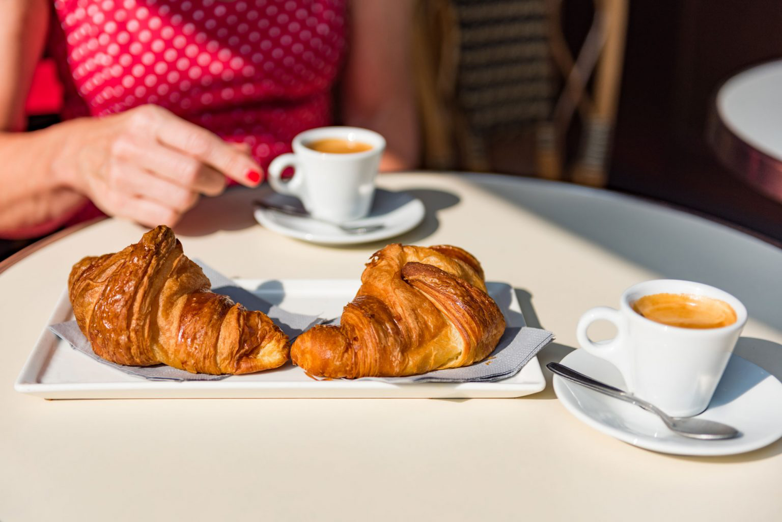 Two croissants on a delicate white dish.