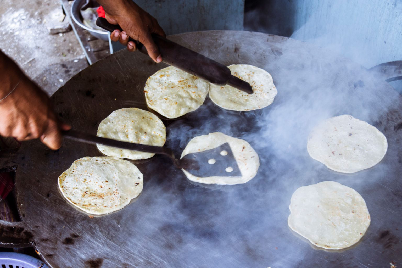 A person cooking small paratha flat bread.