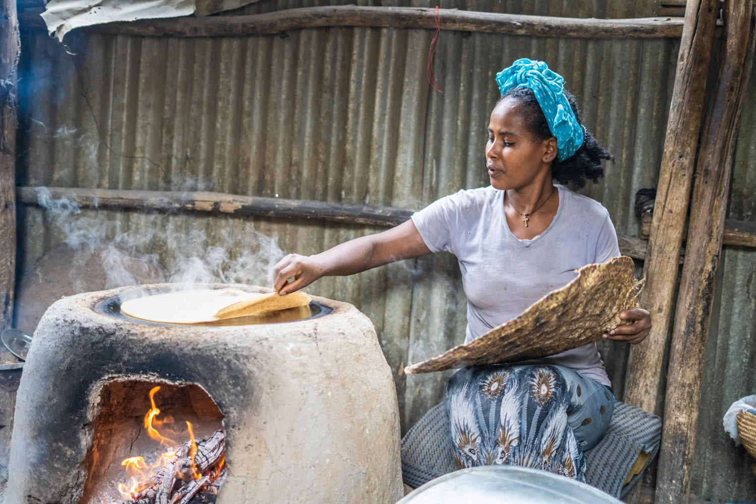 A woman slowly lifting the edges of Ethiopian flatbread.