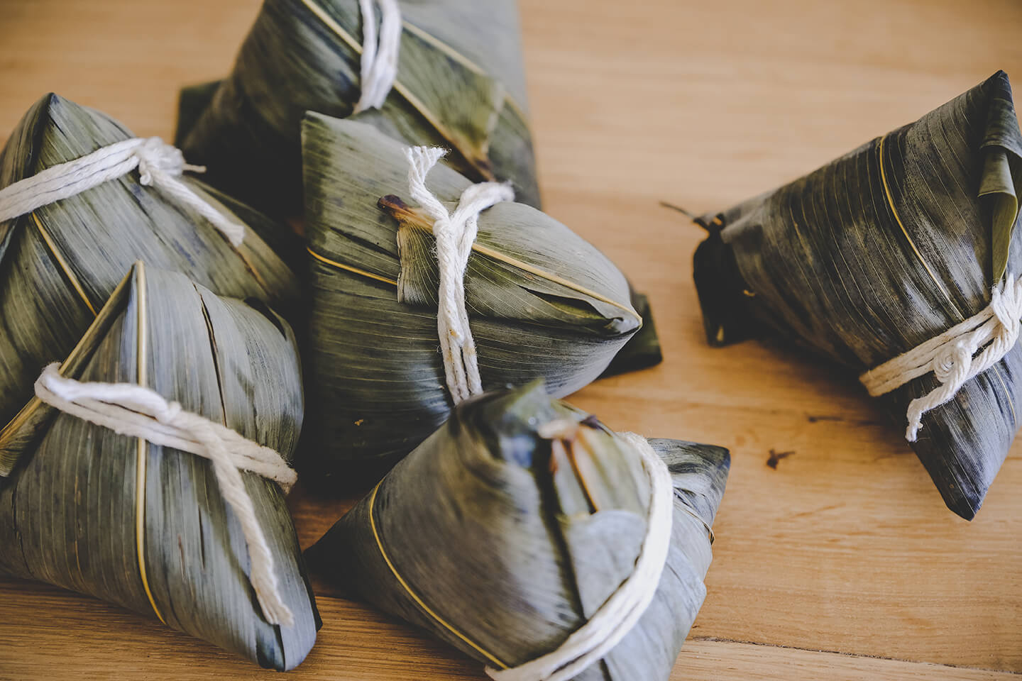 Bundles of food wrapped in bamboo leaves tied shut with twine.