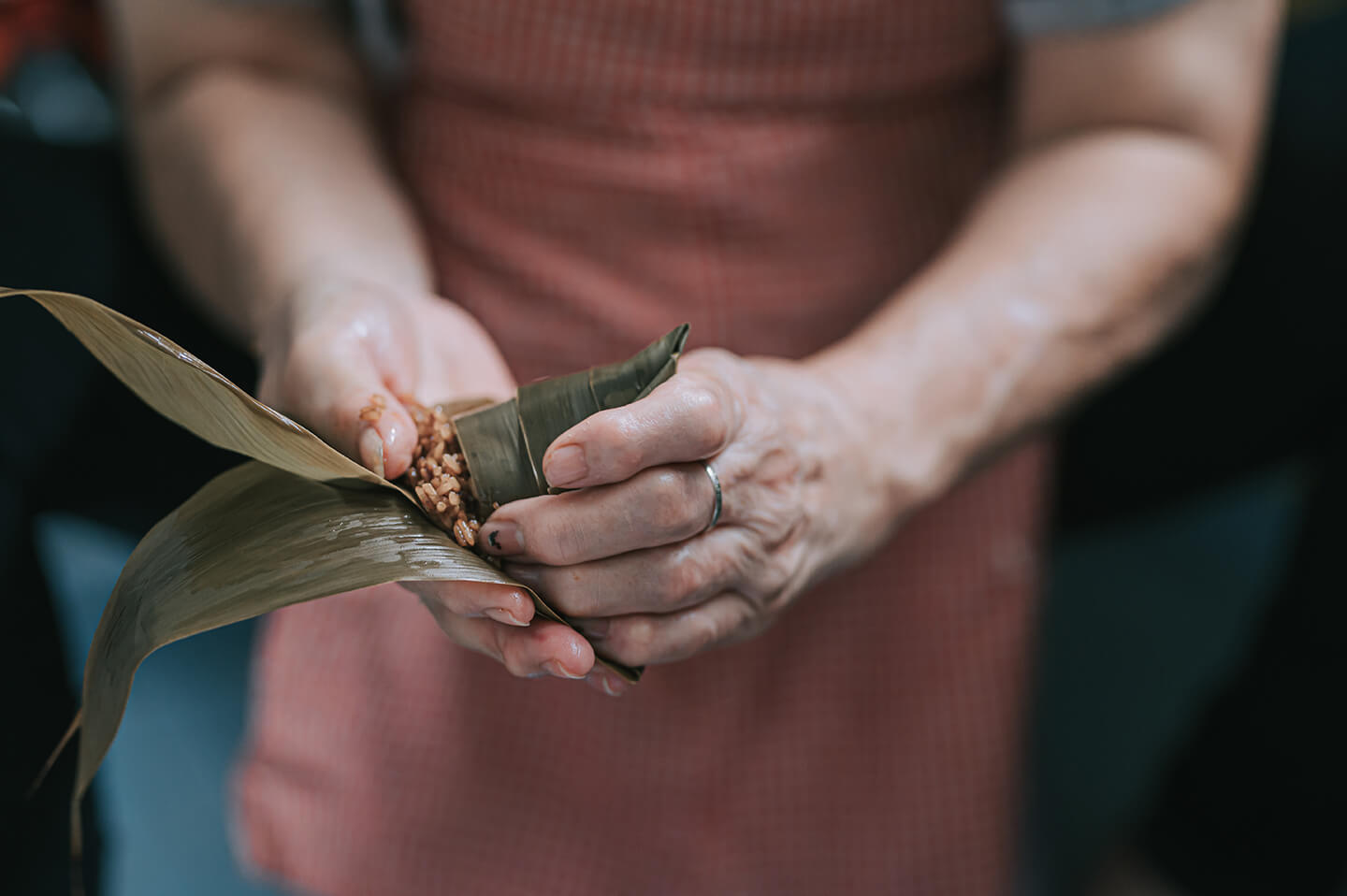 Expert hands gently wrapping rice in bamboo leaves.