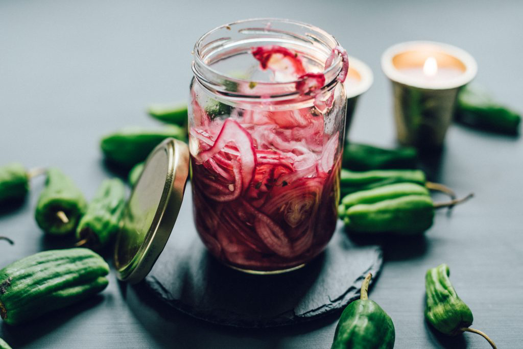 A small, open glass jar filled with sliced, pickled red onion.