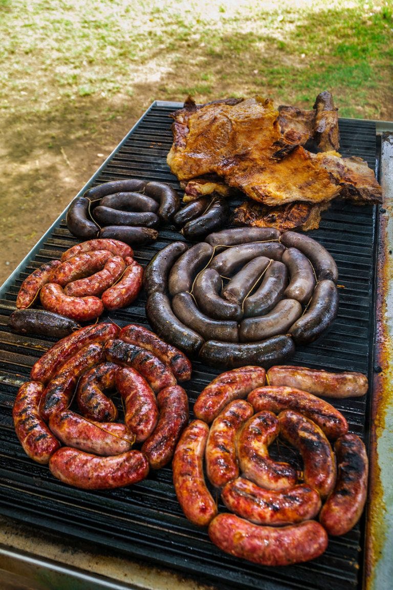 A variety of sausages and meats on a grill.
