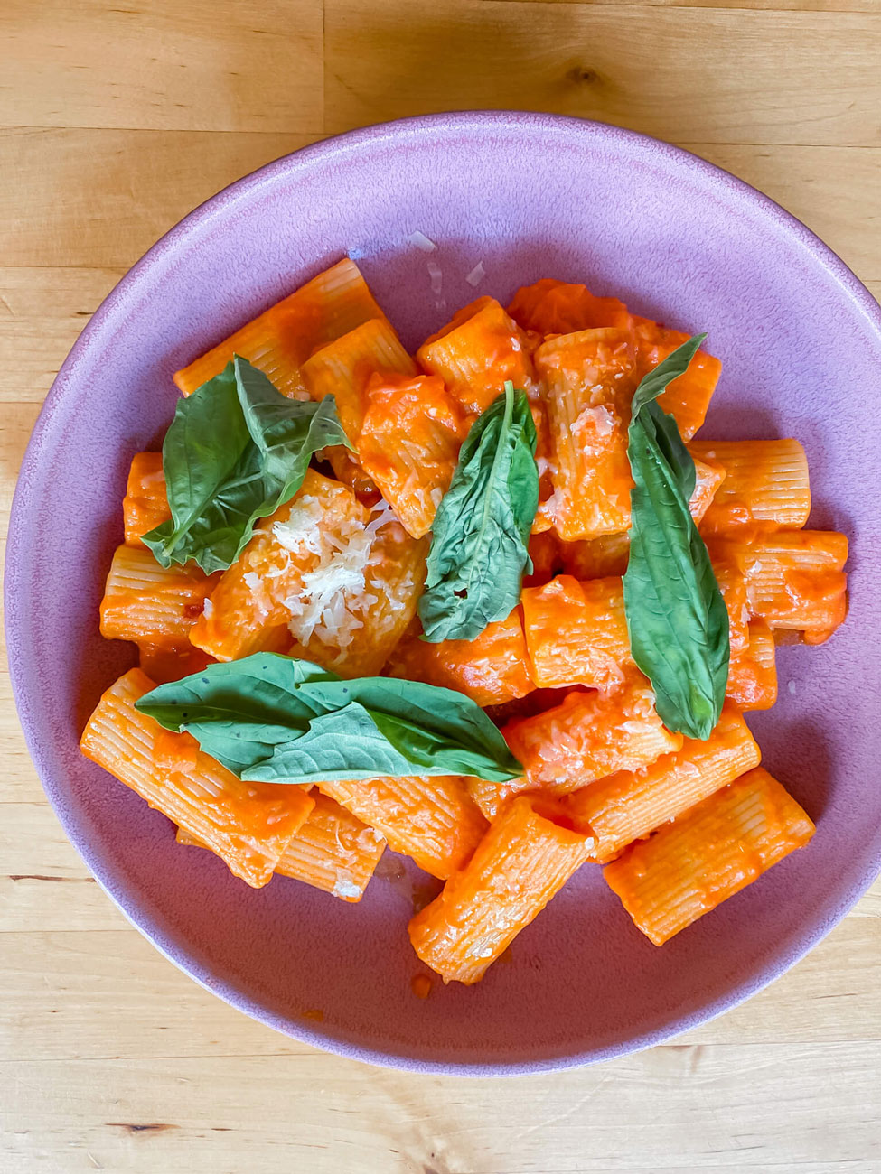 A plate of vodka sauce pasta topped with basil.