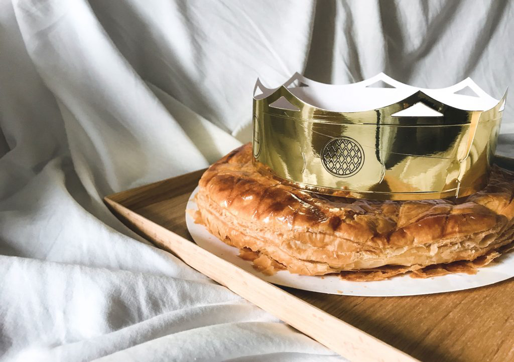 A buttery galette des rois adorned with a shiny paper crown.