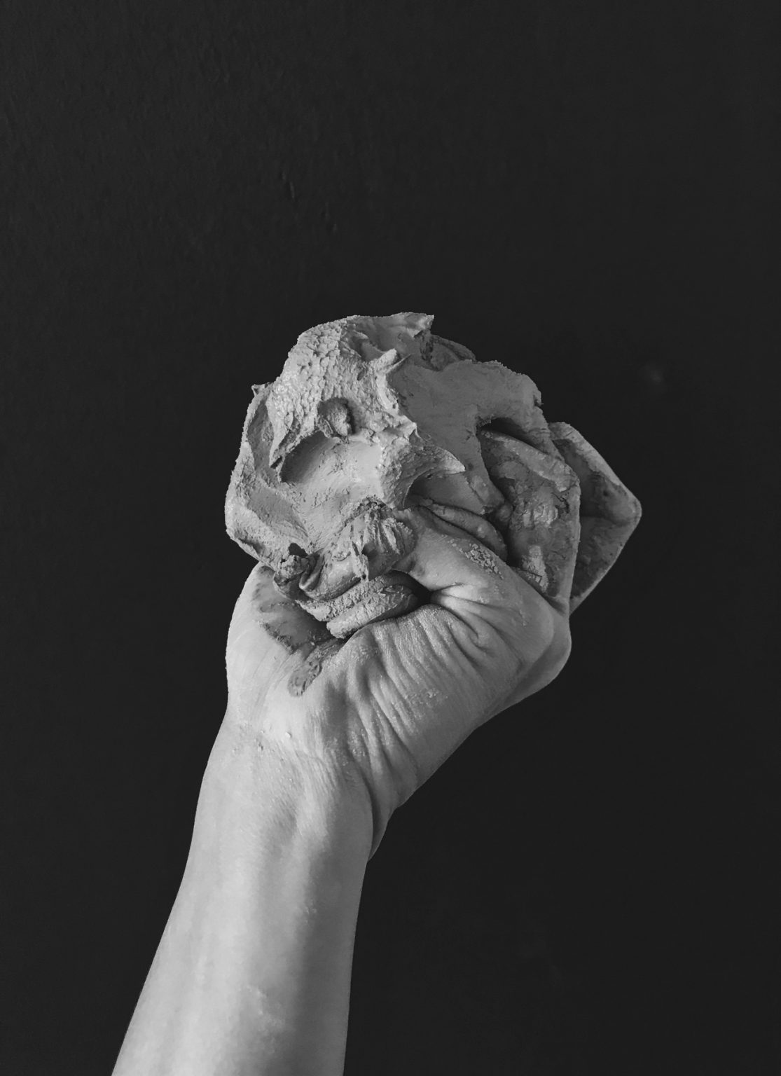 A hand holding a large wad of clay.