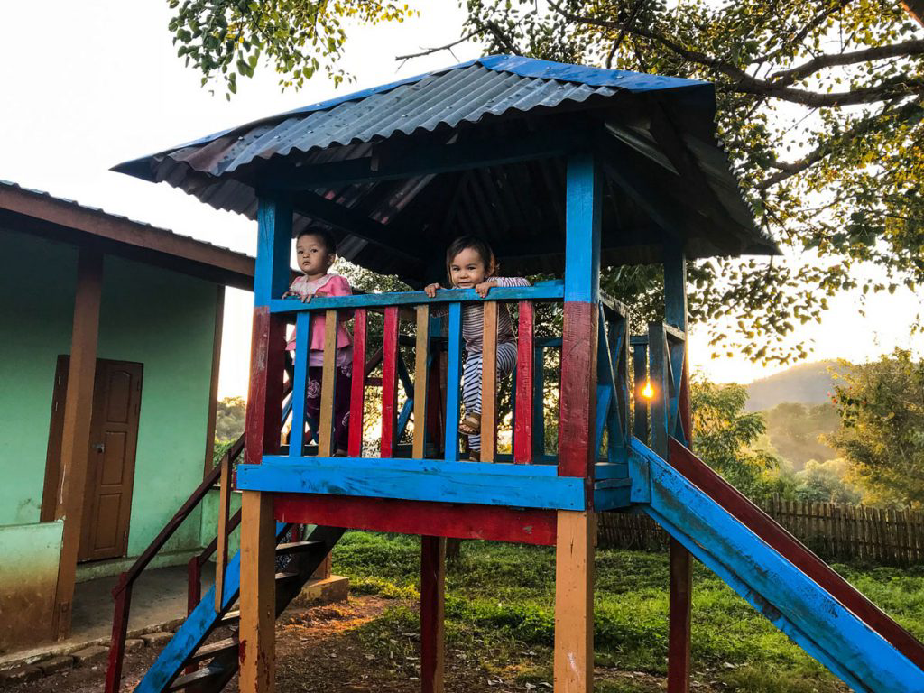 Two children playing on a blue and red playset.