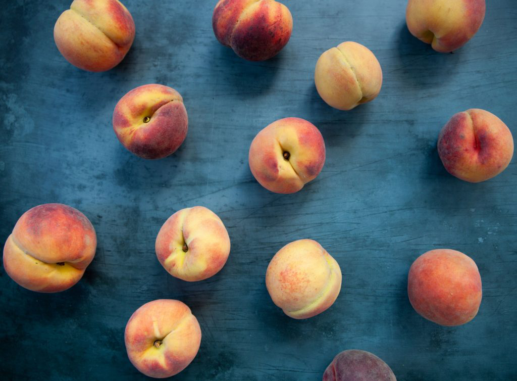 Peaches scattered along a large blue table.