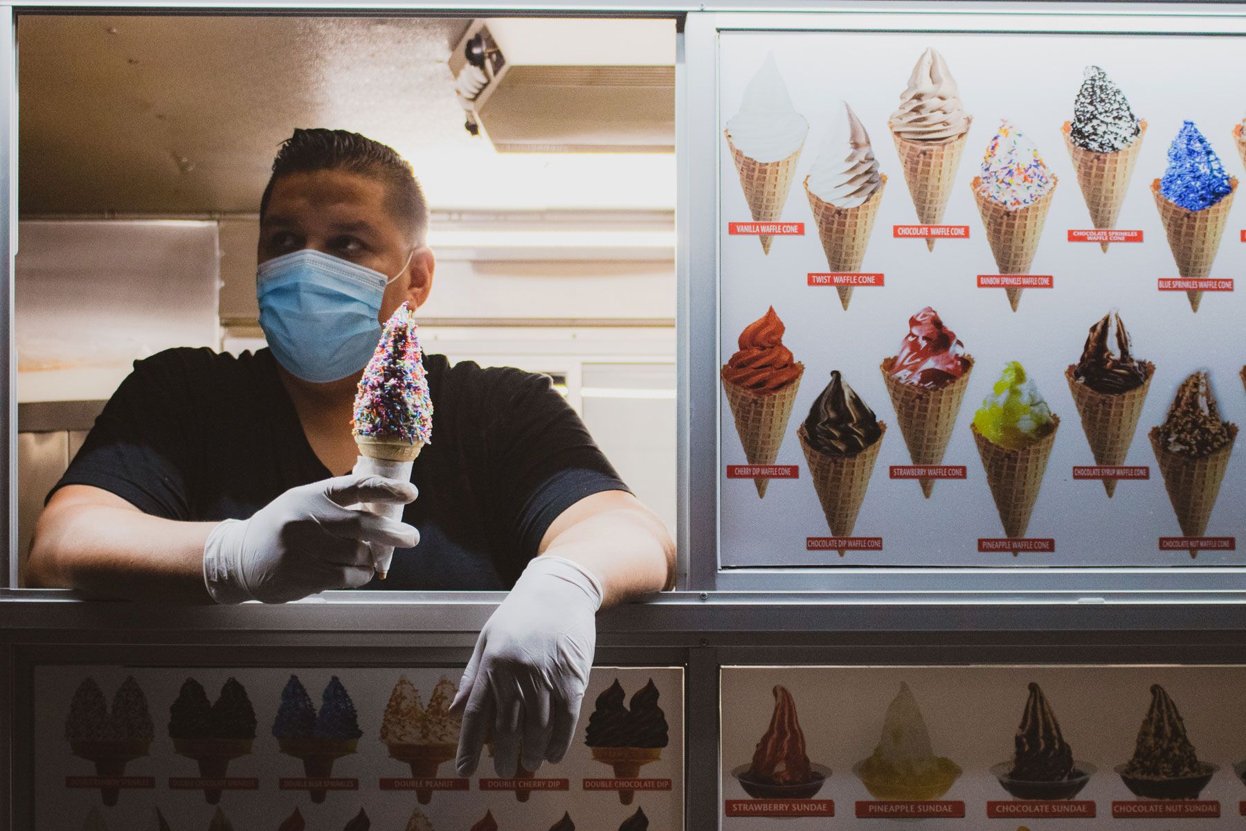 Andy Alvarez inside his ice cream truck holding an ice cream cone loaded with sprinkles.