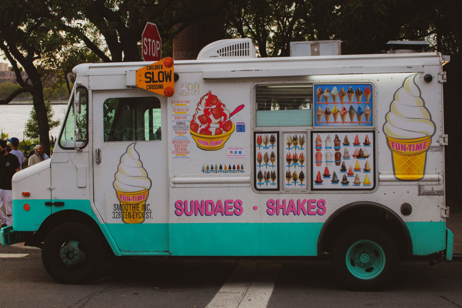 A white ice cream truck decked out with colorful, bright ice cream signage.