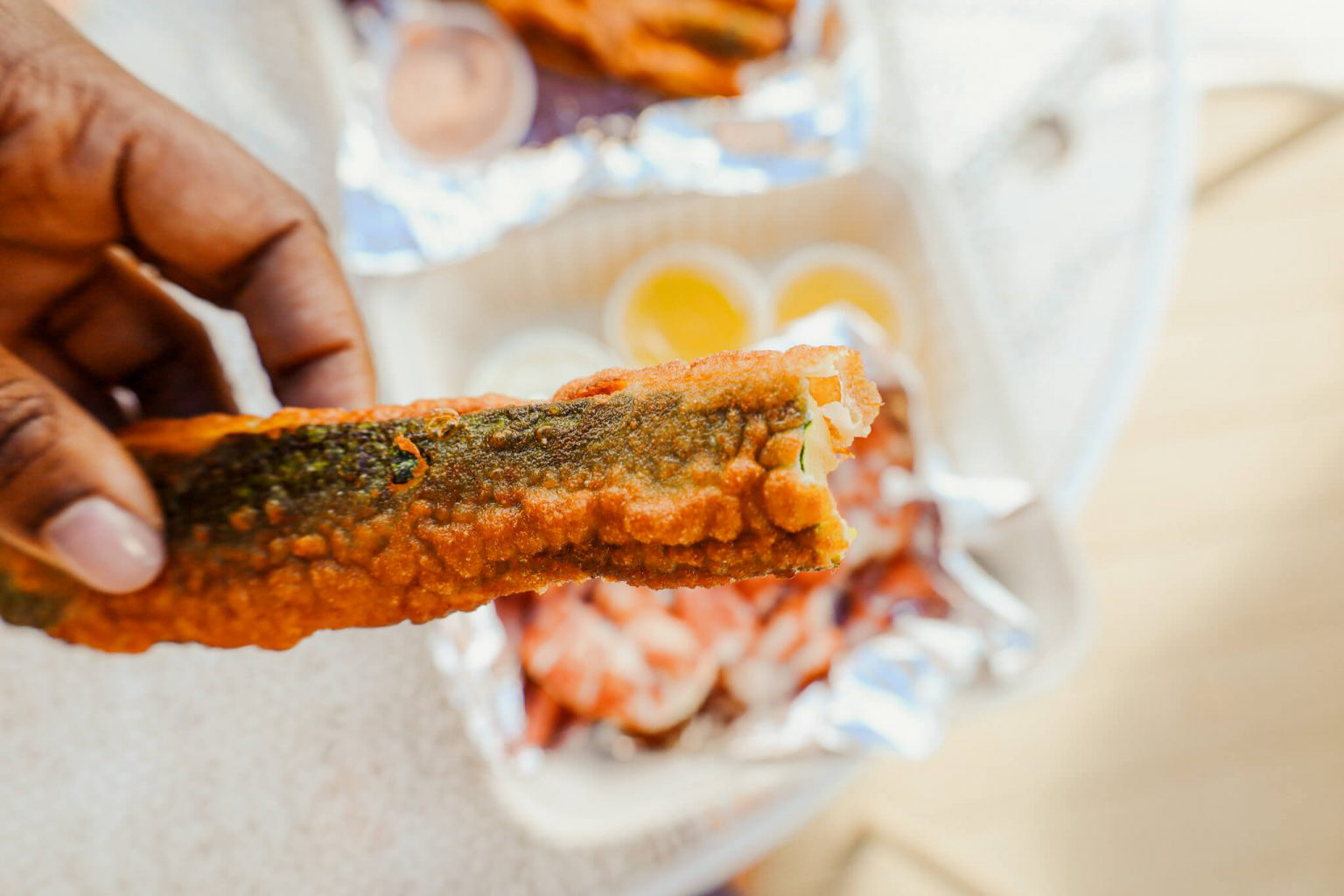 A person holding a fried zucchini.