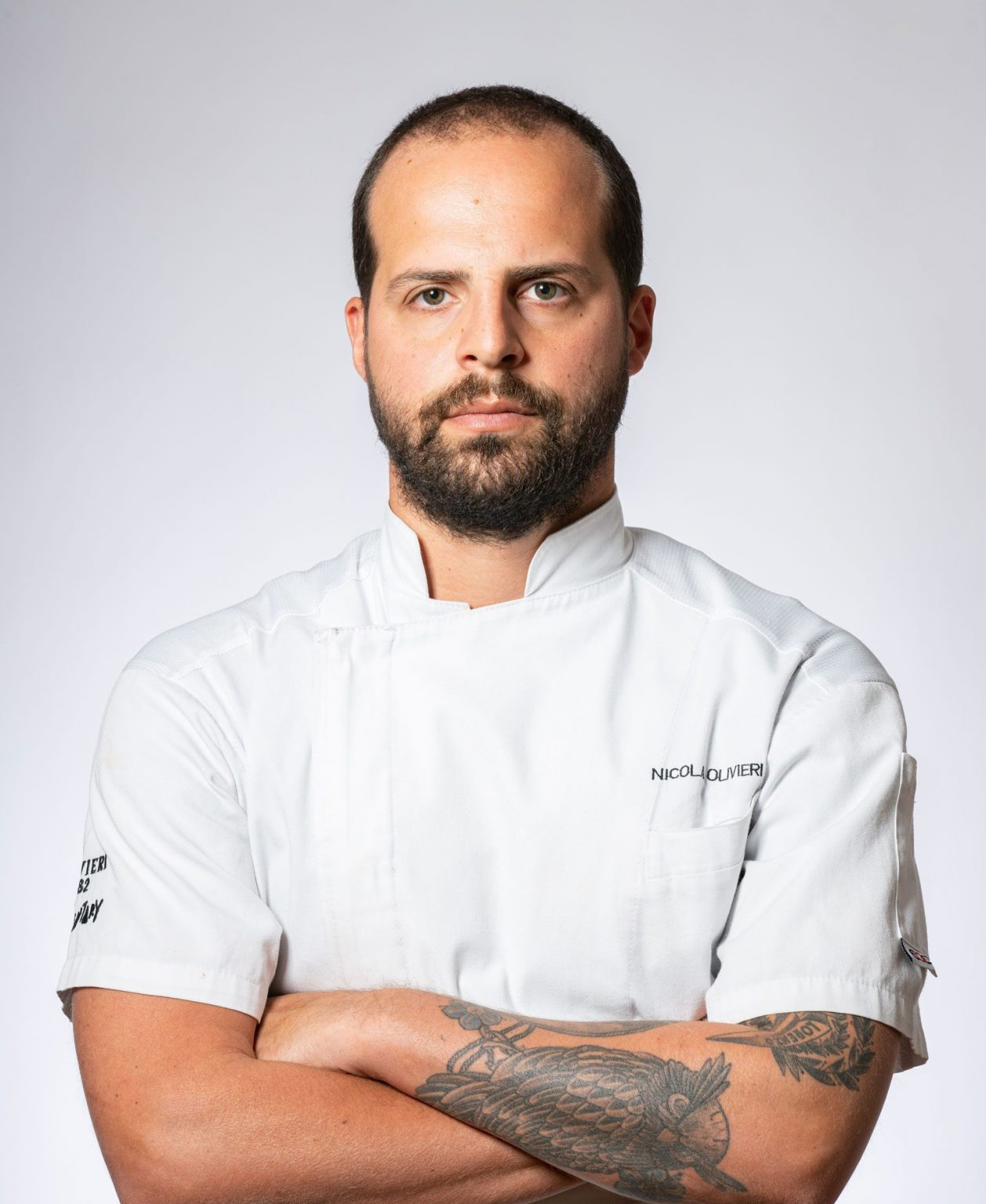 A professional portrait of Nicola Olivieri in his chef's uniform.