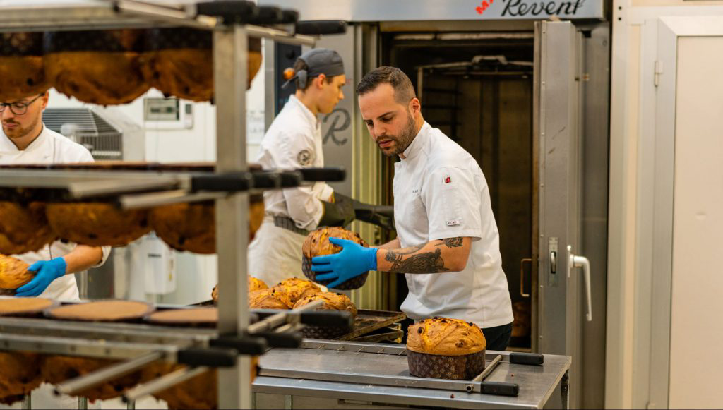 Olivieri handling freshly baked panettone loaves.