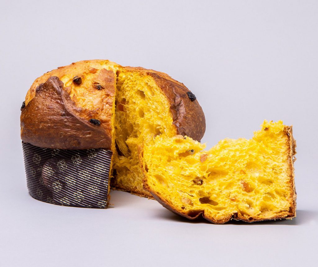 A loaf of panettone with a clean slice resting next to it.