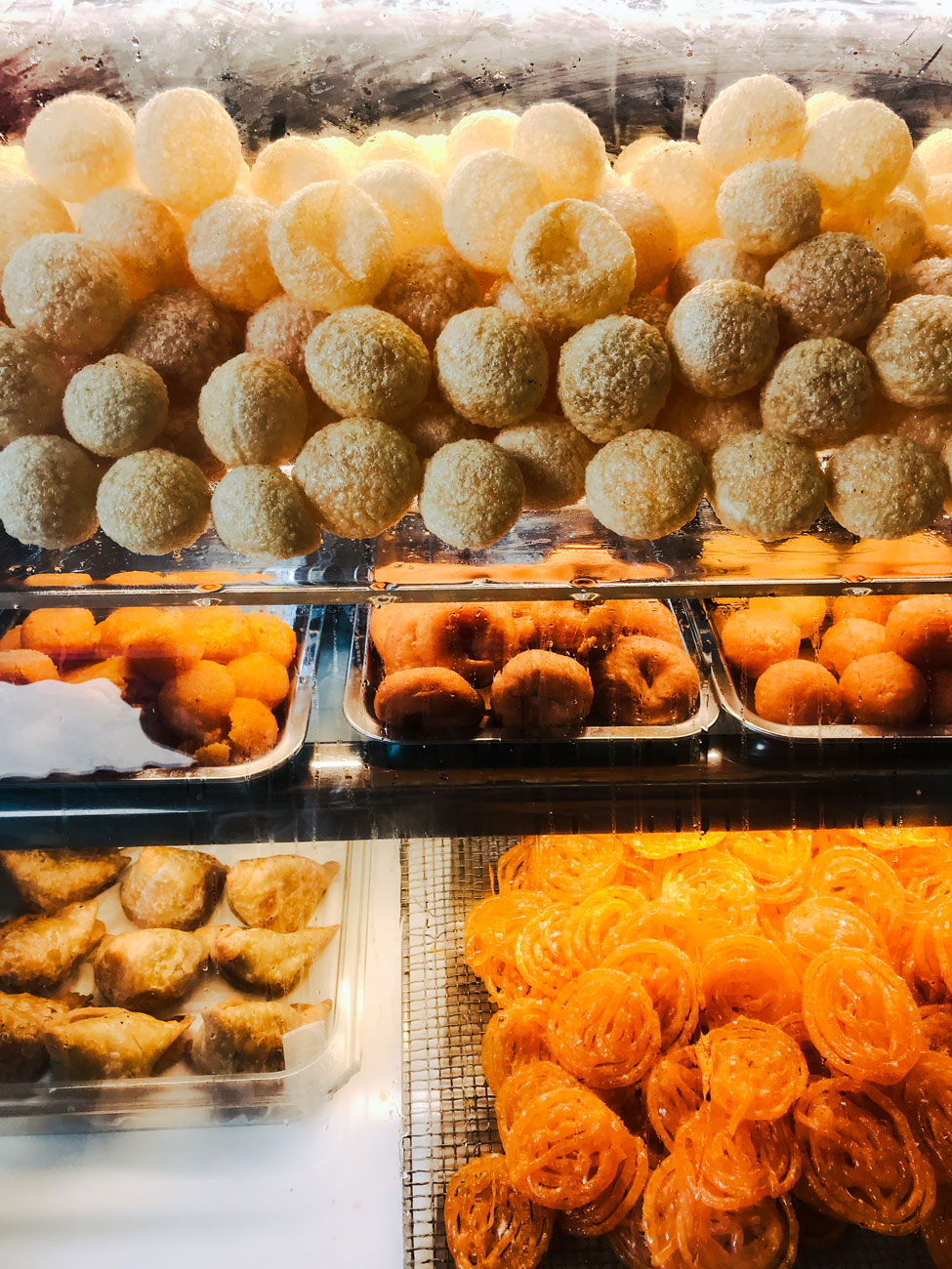 A display of sweets and puri, bite-sized deep-fried hollow dough balls.