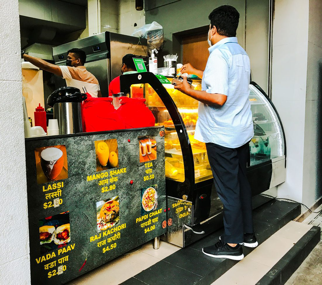 A person ordering food at a small Indian food stall.