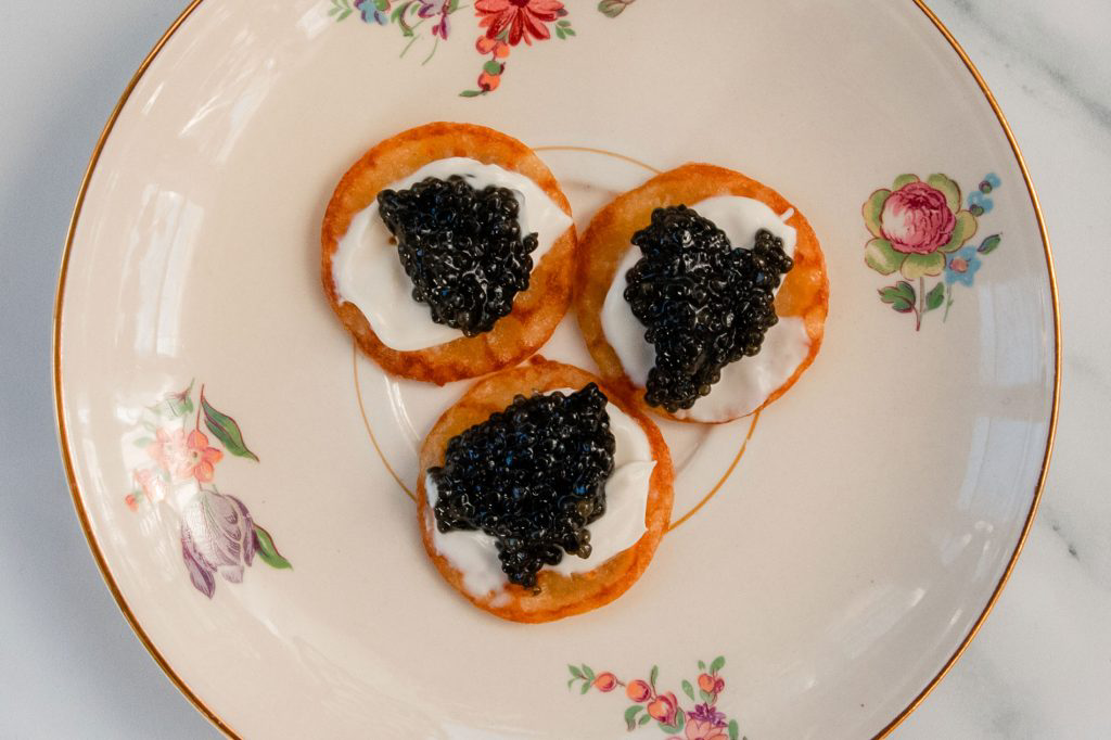 Dollops of black caviar resting on top of freshly made blinis.