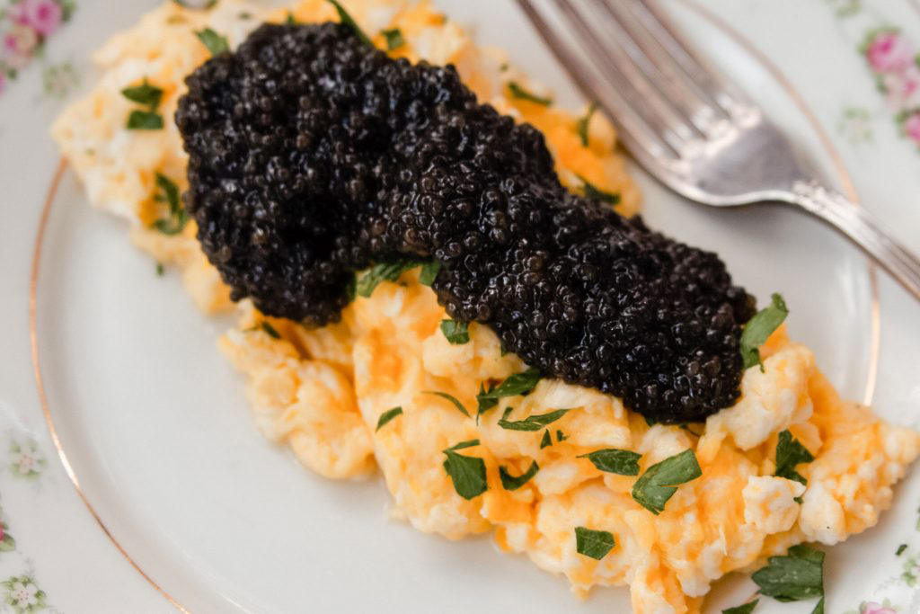 A hefty serving of black caviar resting on top of scrambled eggs.