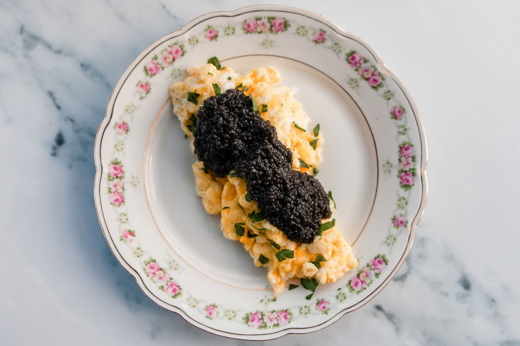 A plate of scrambled eggs topped with black caviar.