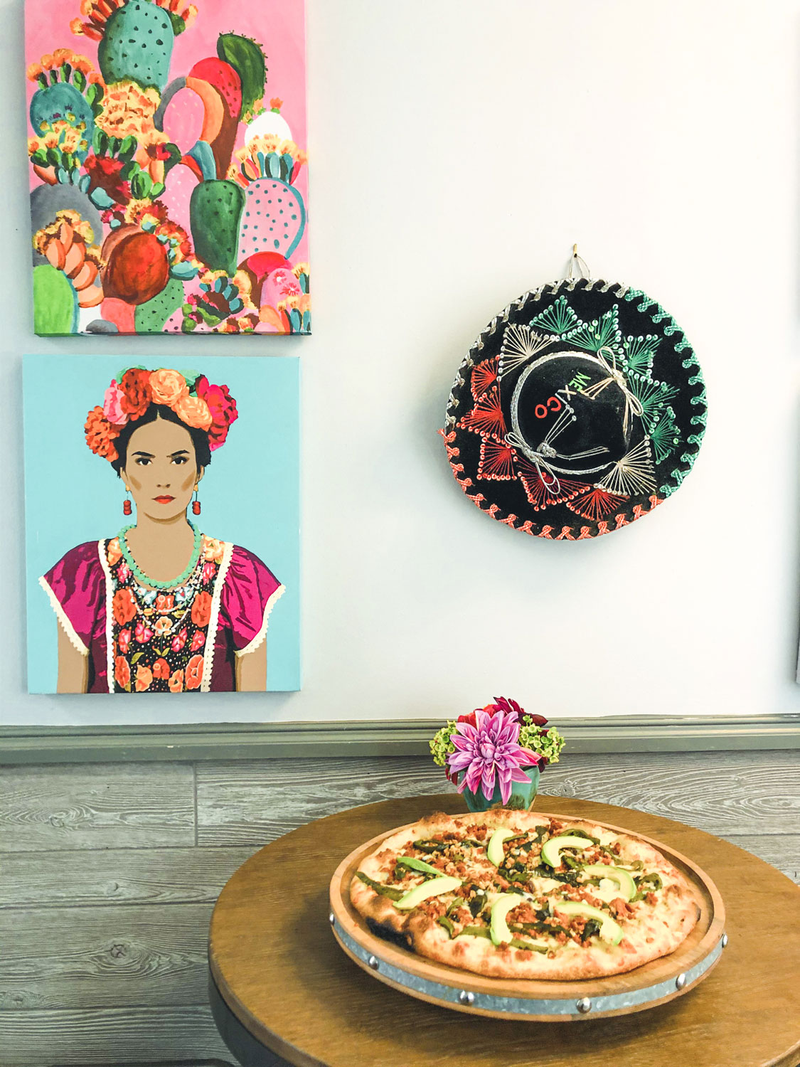 Mexican pizza accompanied by vibrant, colorful Mexican art.