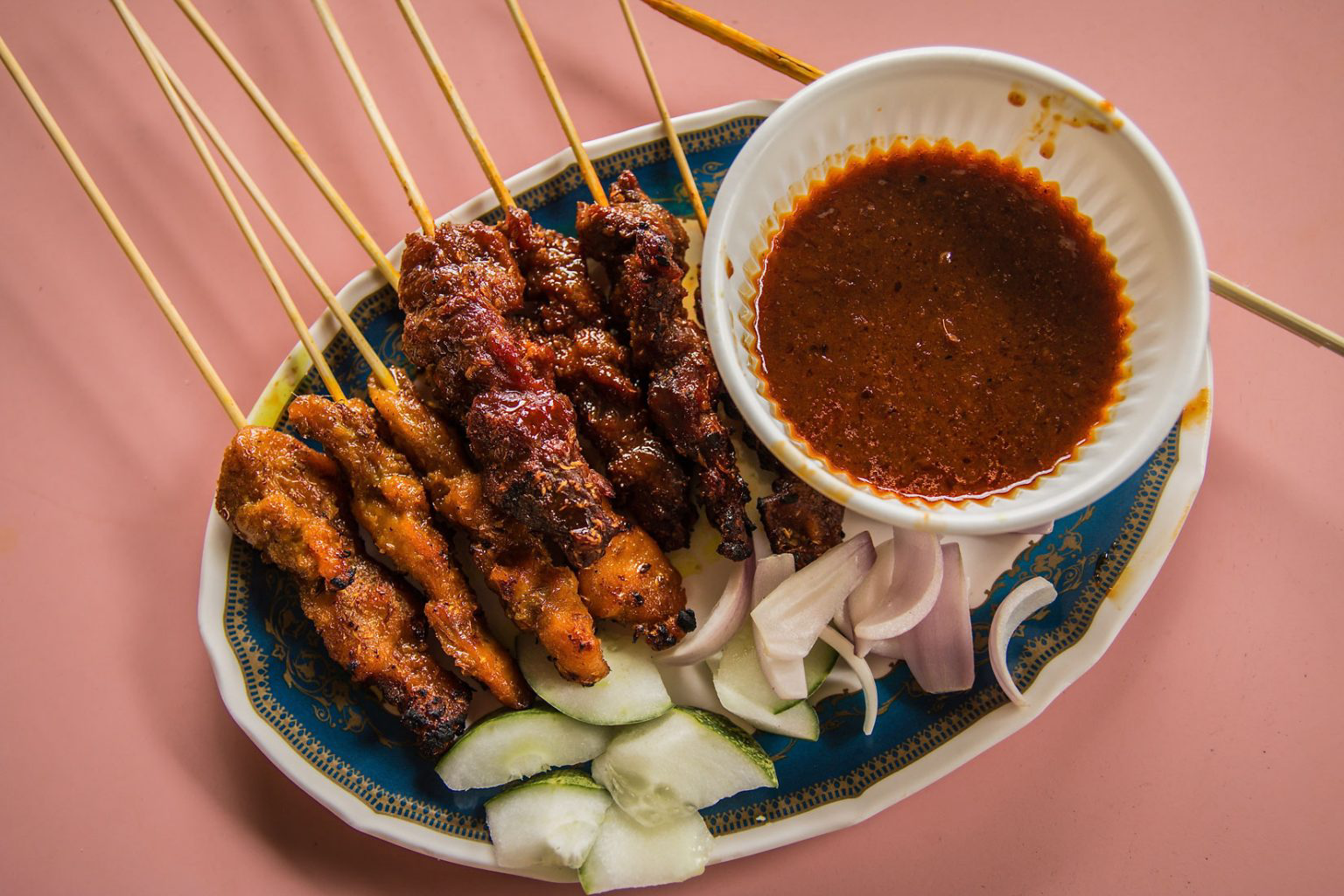 An ornate dish filled with Singaporean satay and a dish of peanut sauce.