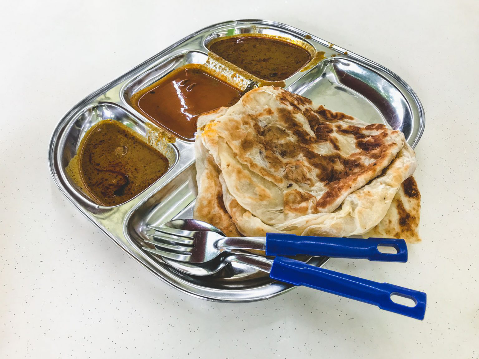 A silver tray filled with Roti John and a variety of sauces.