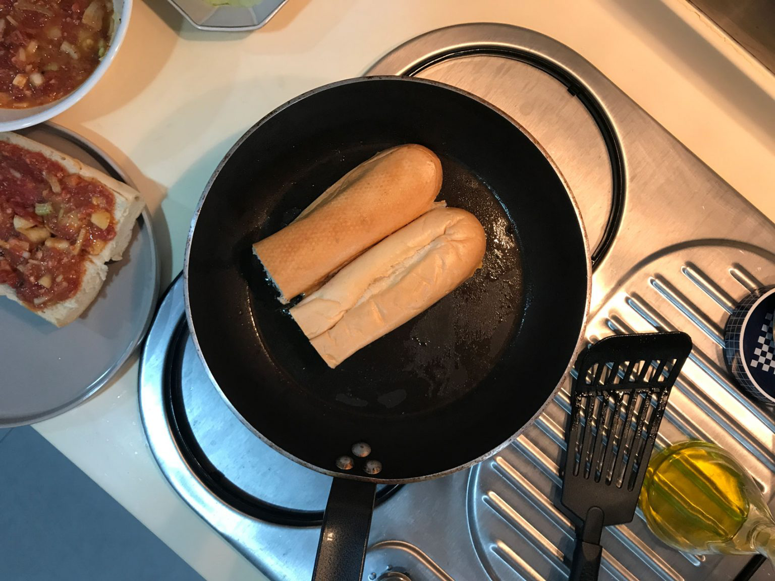 Two halved loaves toasting in a black skillet.