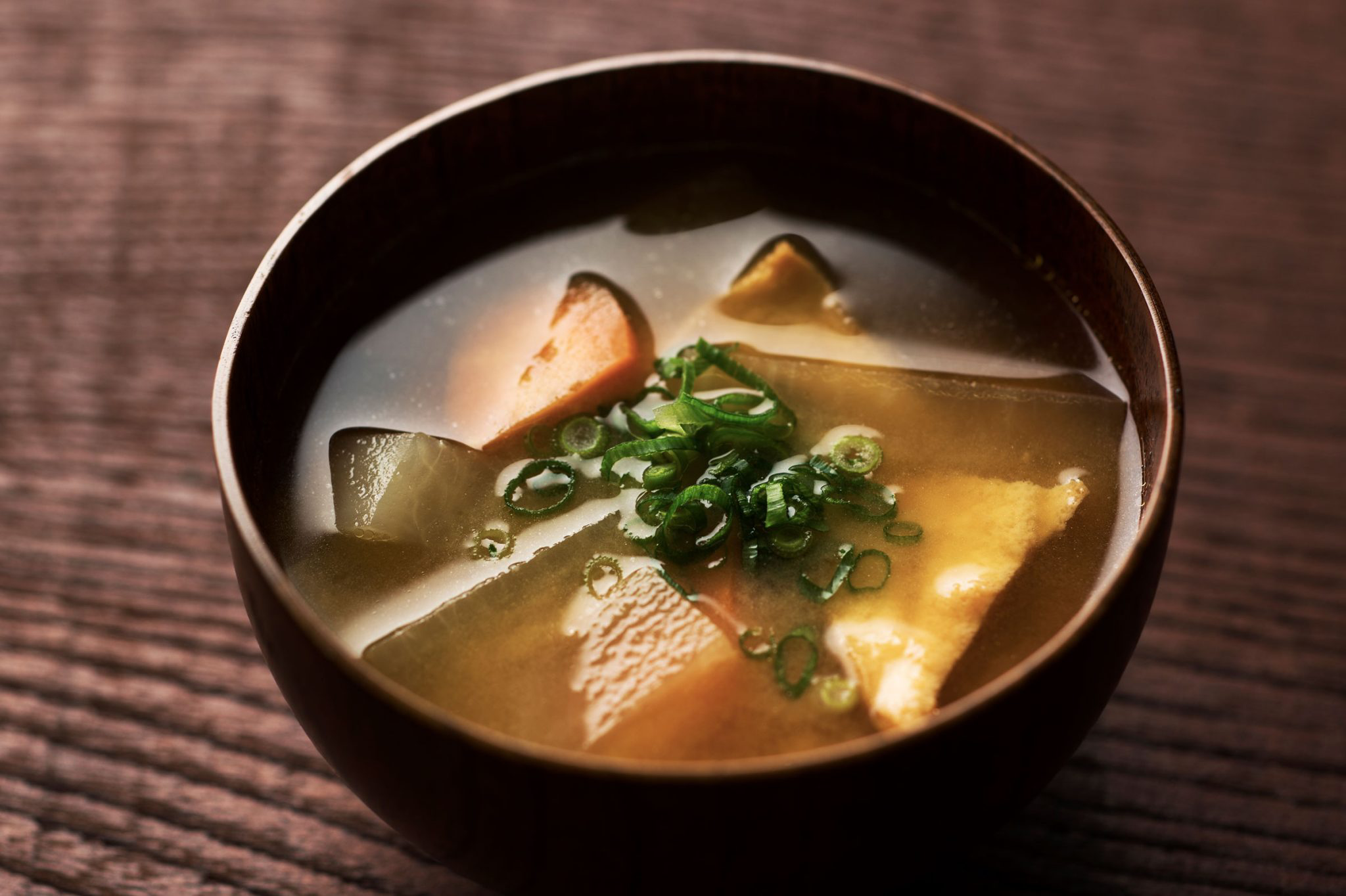 A wooden bowl filled with miso soup made with green tea.