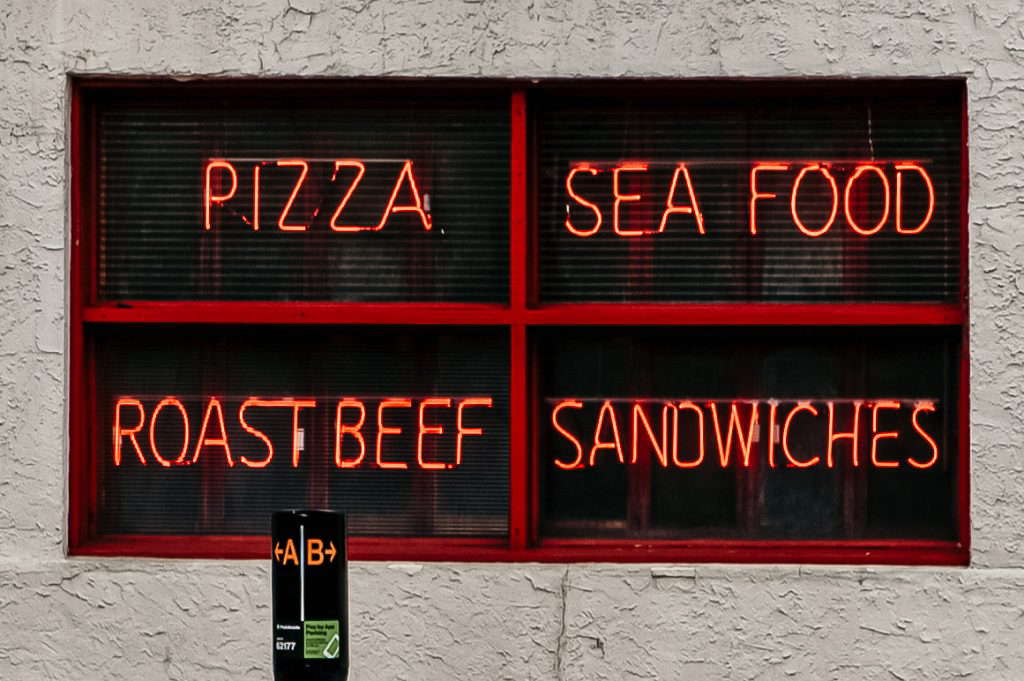 Four red neon signs displaying various types of food.