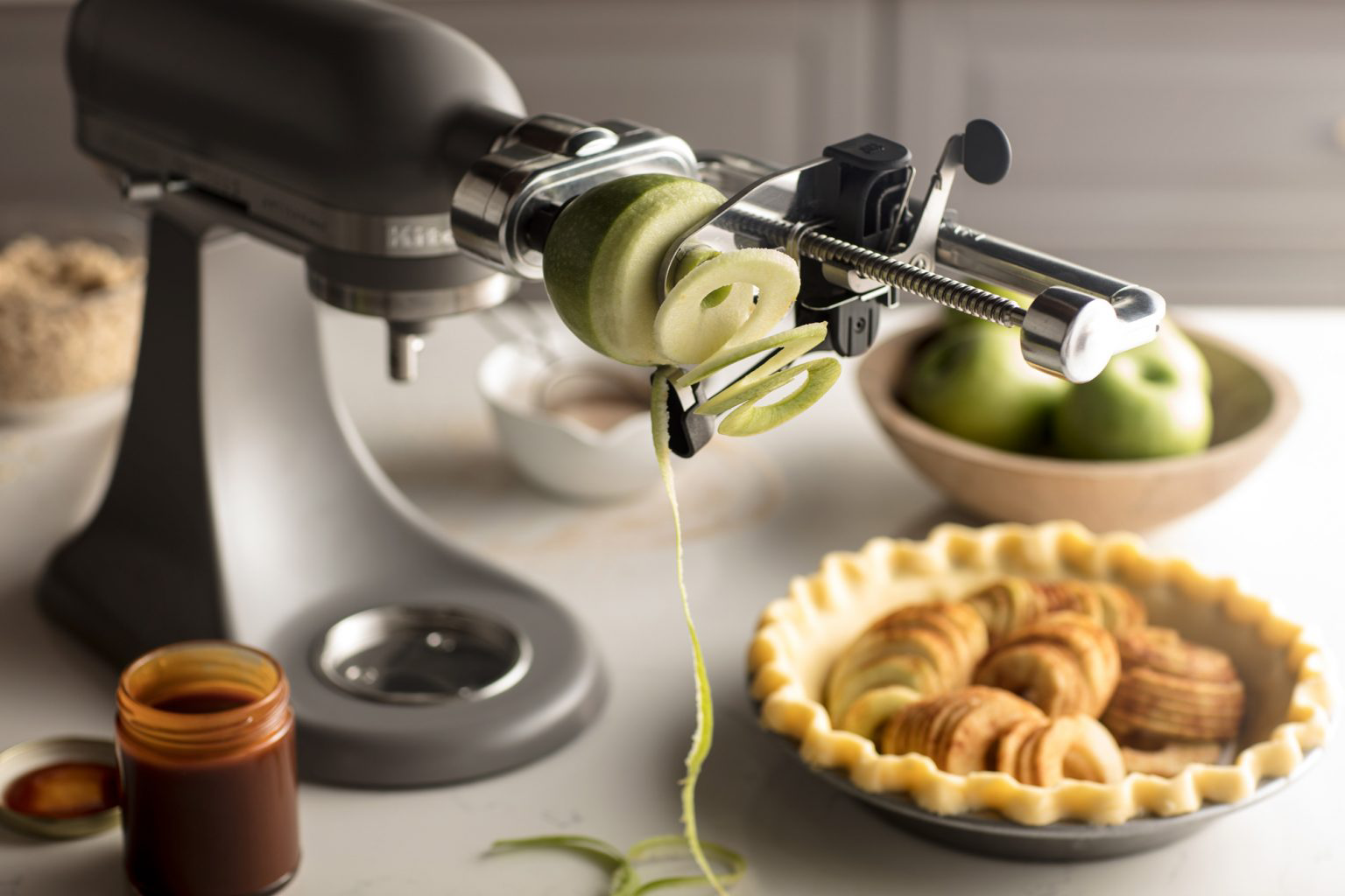 A KitchenAid® stand mixer spiralizing a green apple.