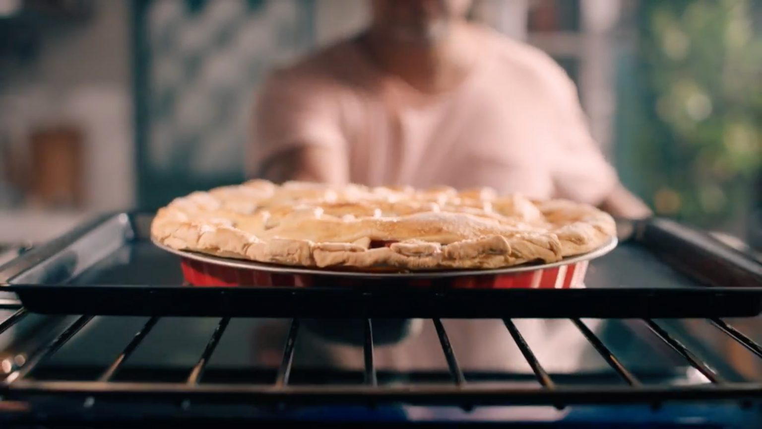A person pulling out a pie from the oven.