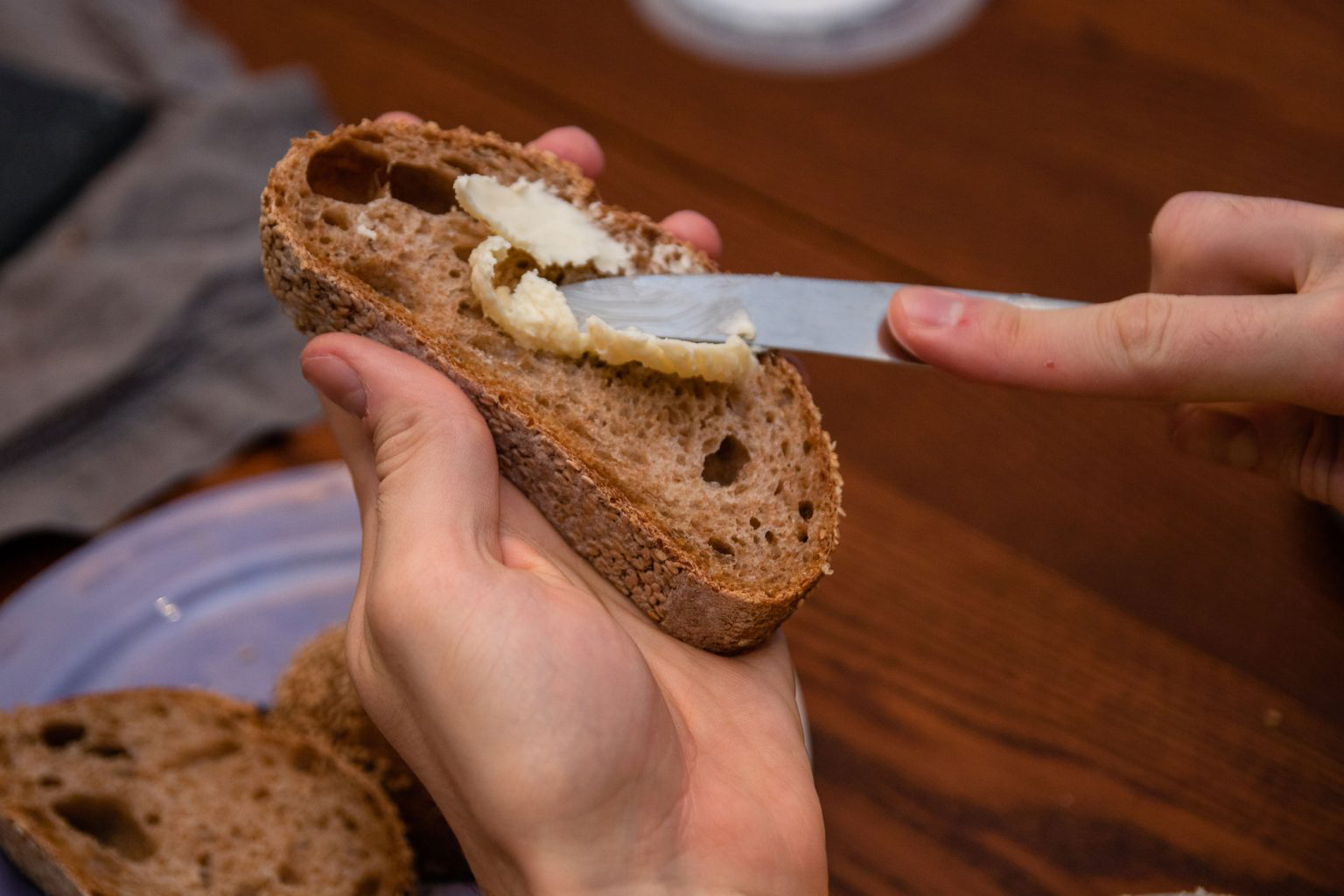 A person buttering a slice of bread.