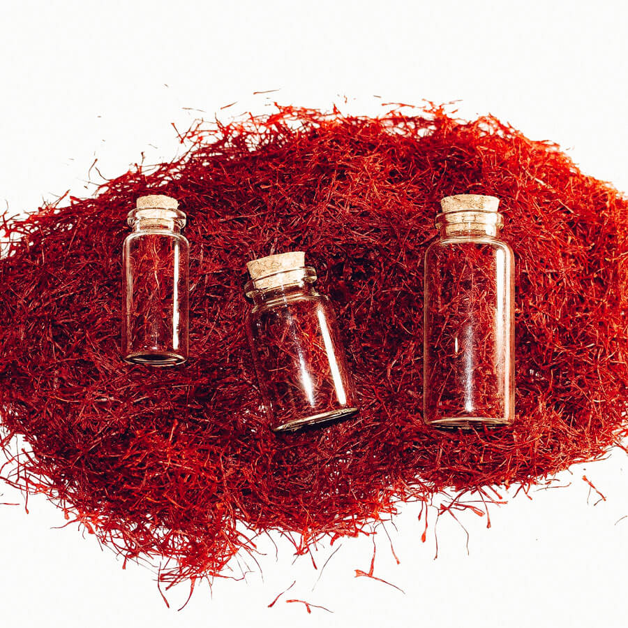 Three small, corked bottles of saffron resting on a pile of saffron.