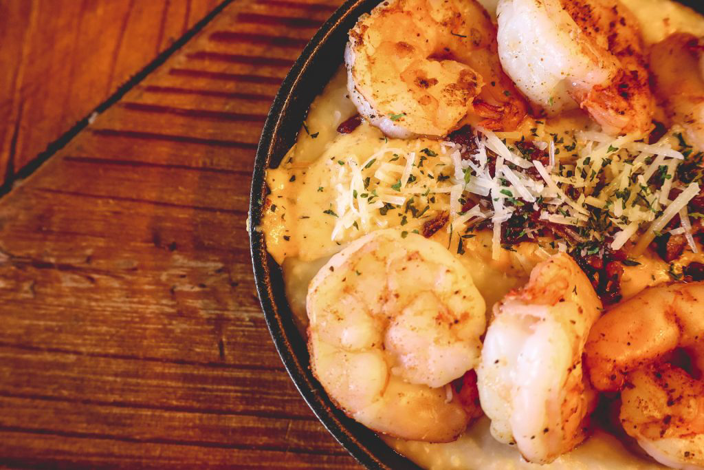 A closeup of a cast iron skillet filled with shrimp and grits.