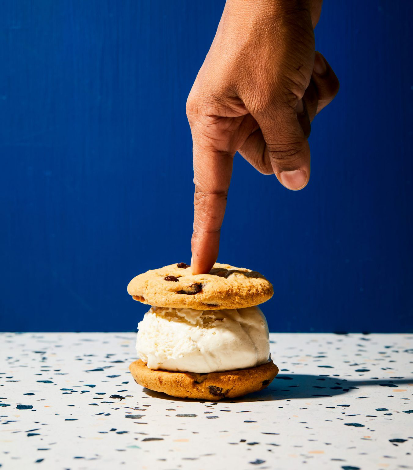 A person pressing on an ice cream sandwich.