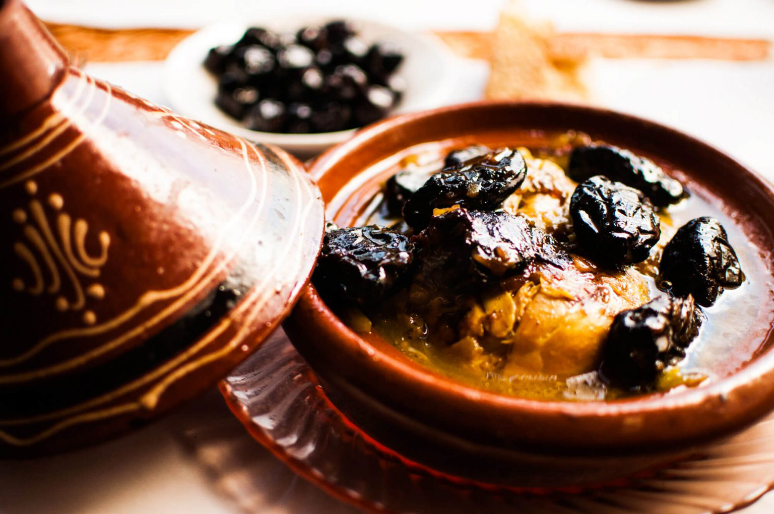 An open tagine filled with broth, cooked dates and other ingredients.