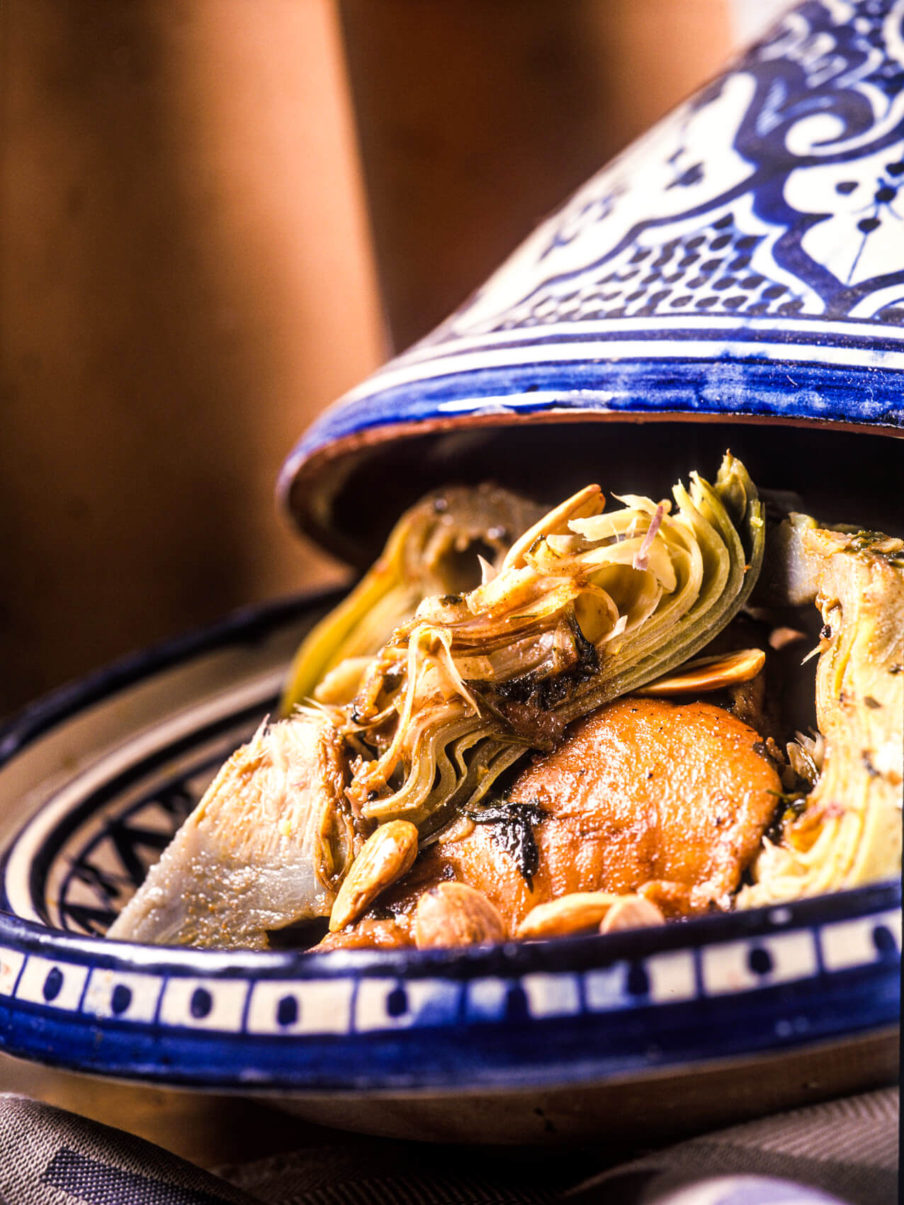 An open tagine filled with shredded artichokes, chicken and other ingredients.