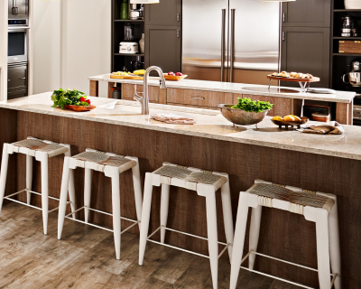 A kitchen island with four stools and appetizers on the counter.