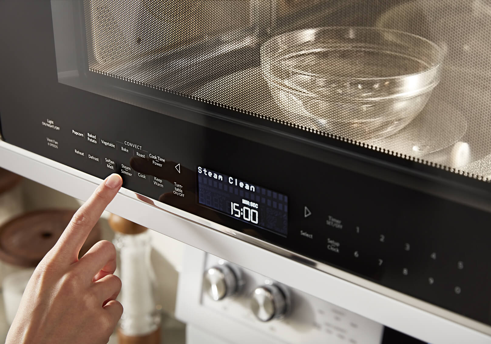 Hand selecting the Steam Clean option on a microwave console