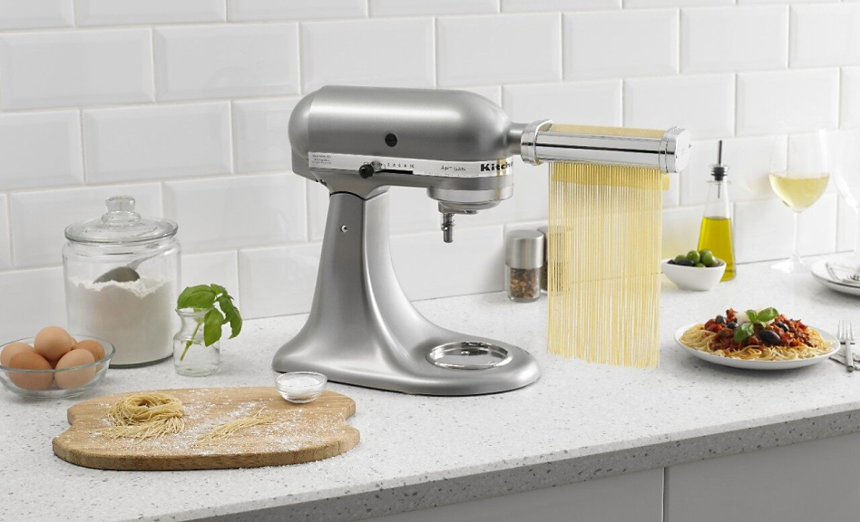 KitchenAid® stand mixer with pasta cutter attachment cutting pasta dough into thin strips.
