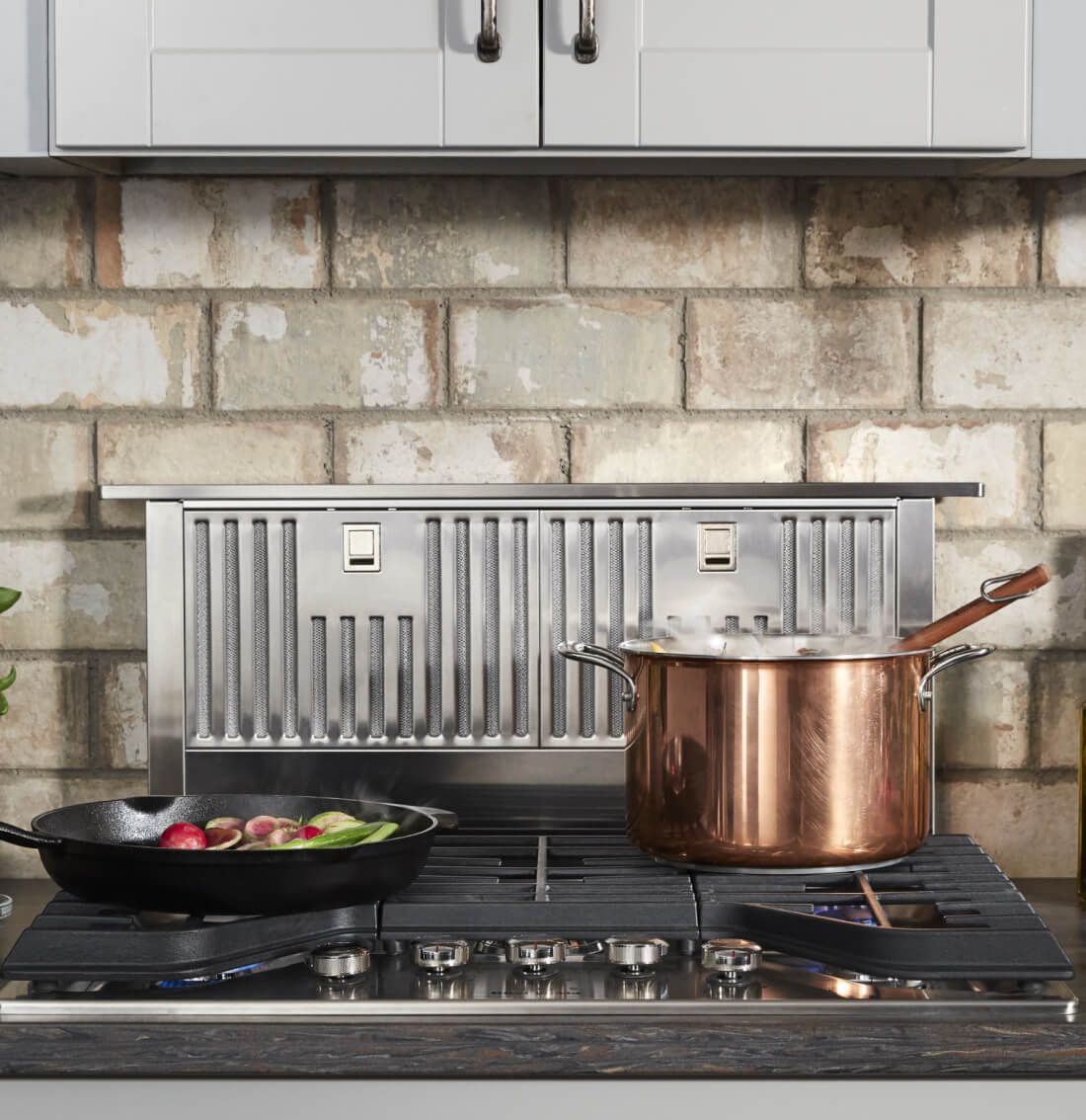 Retractable downdraft hood behind a gas range