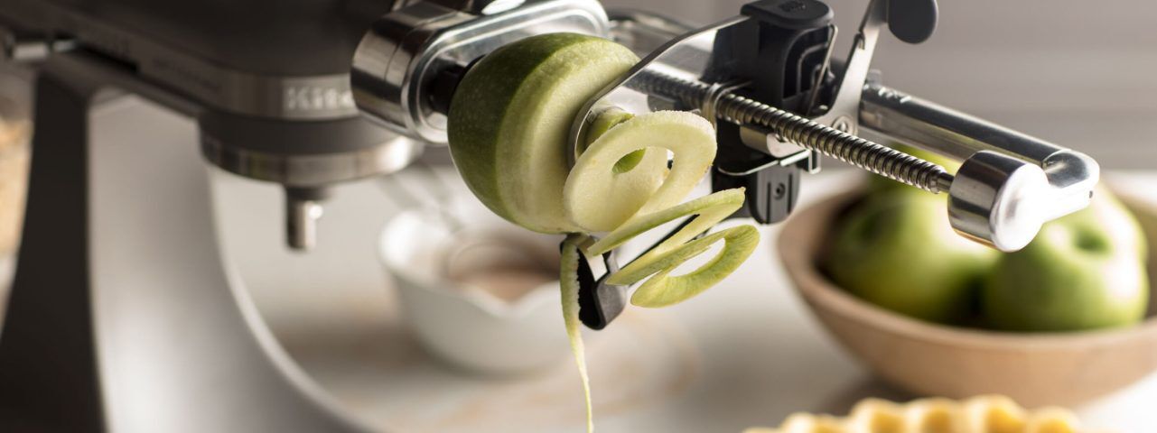 A spiralizer attachment spiralizing a green apple.
