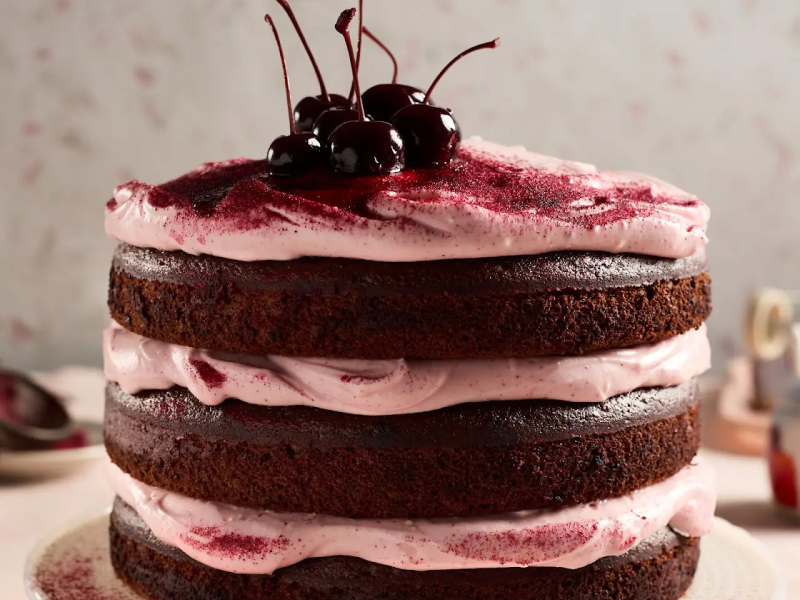 Chocolate cake layered with pink cream and topped with cherries
